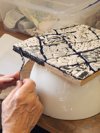 Une personne qui jointe son travail à la mosaïque